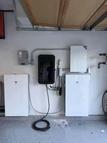 Tesla batteries and associated equipment in a garage.
