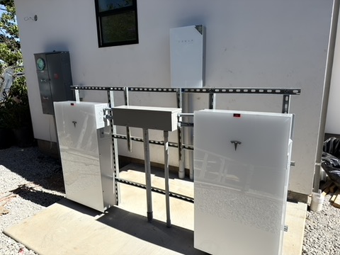Tesla battery units supported on an outdoor mounting frame.
